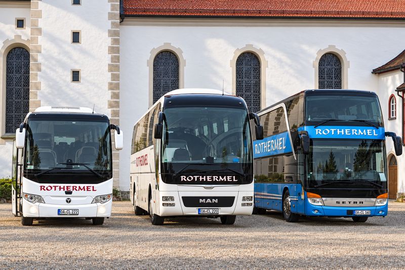 Midibus, Reisebus und Doppeldecker von Rothermel Reisen nebeneinander vor einer Kirche