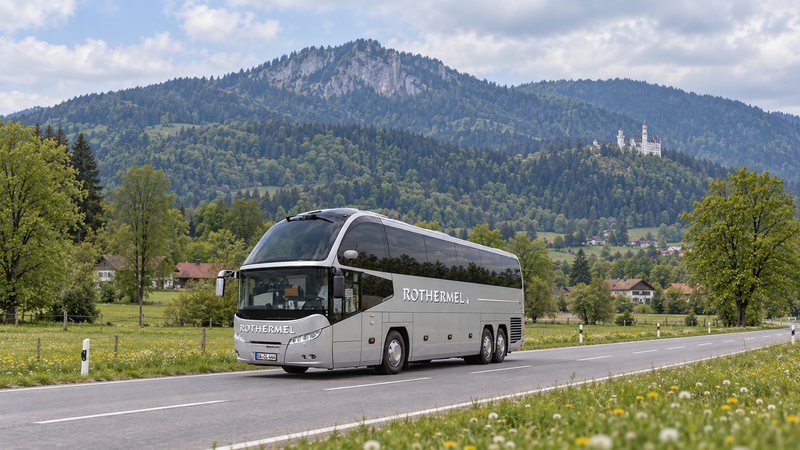 Reisebus von Rothermel Reisen auf einer Landstraße im Ostallgäu, im Hintergrund Schloss Neuschwanstein